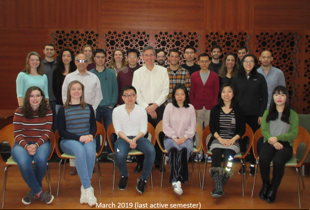 Group photo from March 2019 (Warren Powell's last active semester) showing roughly two dozen graduate students, undergraduates, staff and post-docs seated and standing in three rows in front of a wood-paneled wall